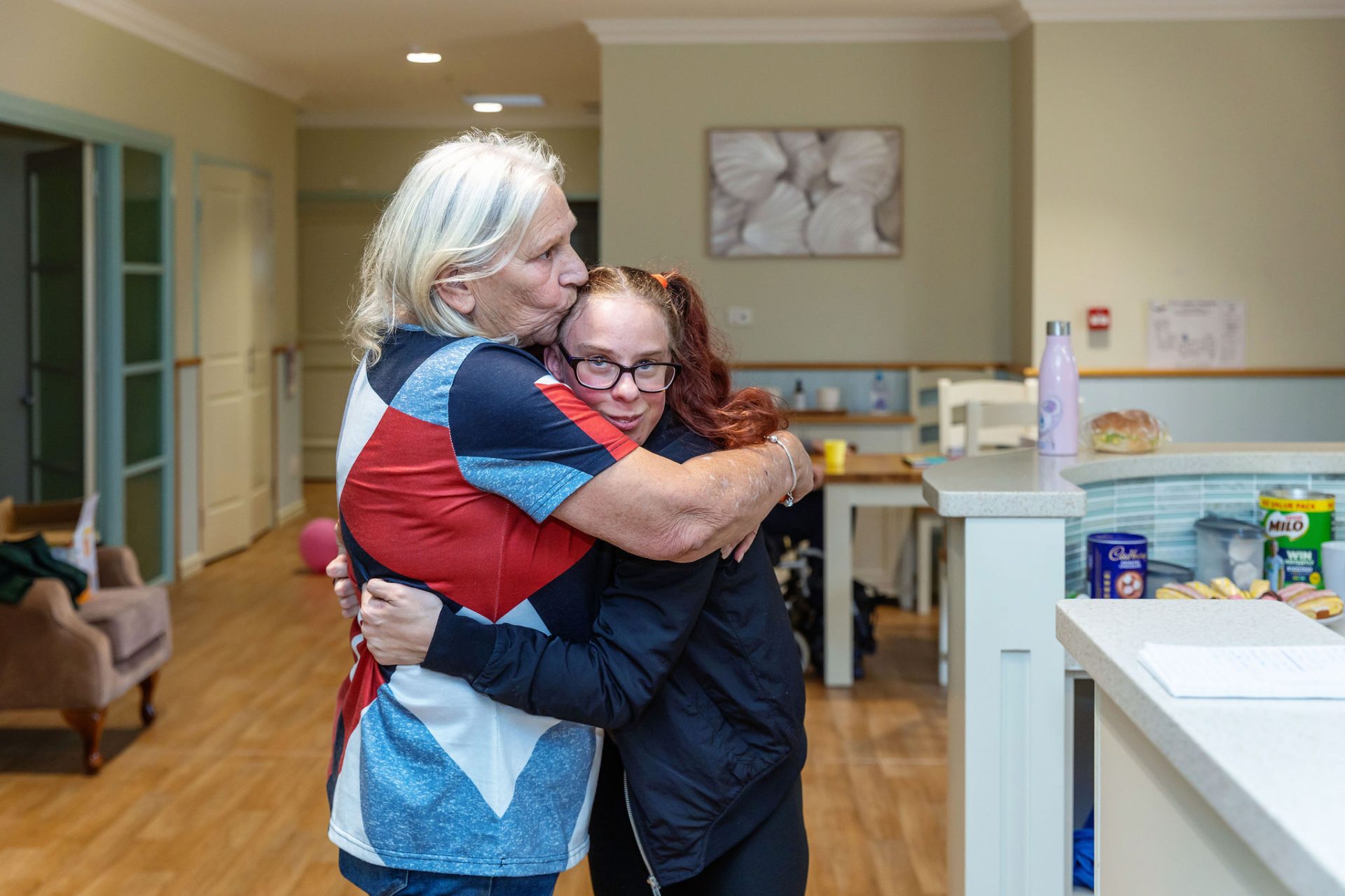 Two ladies hugging in the kitchen