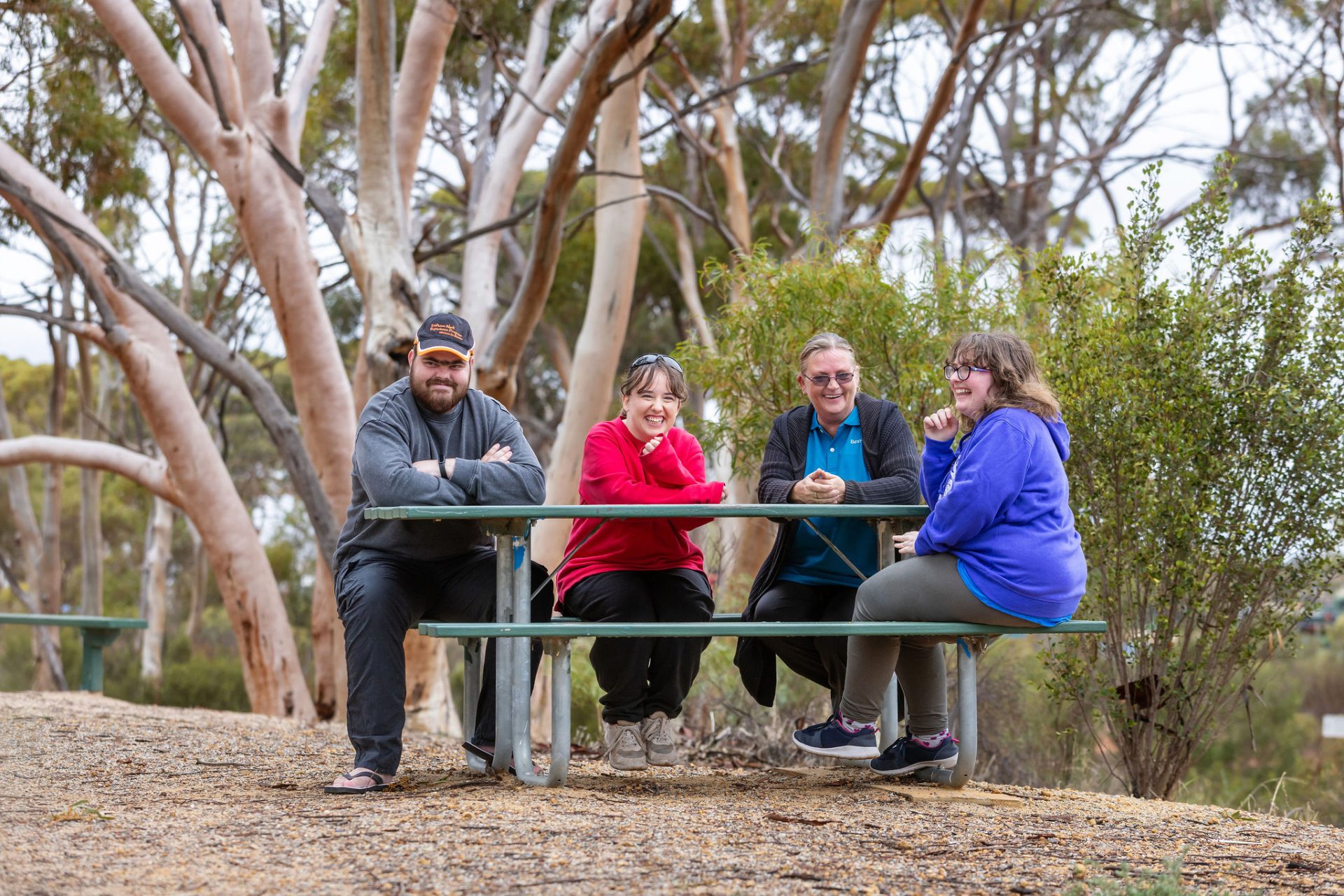 Four people sit chatting and laughing outdoors.