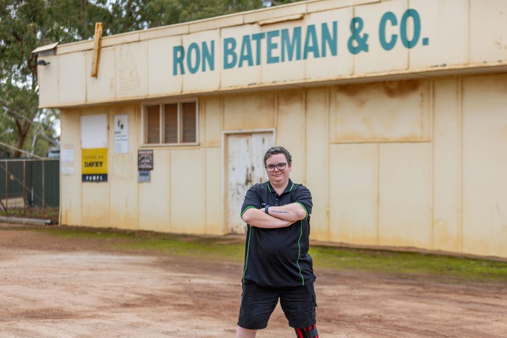 Employee standing proudly in front of their workplace.